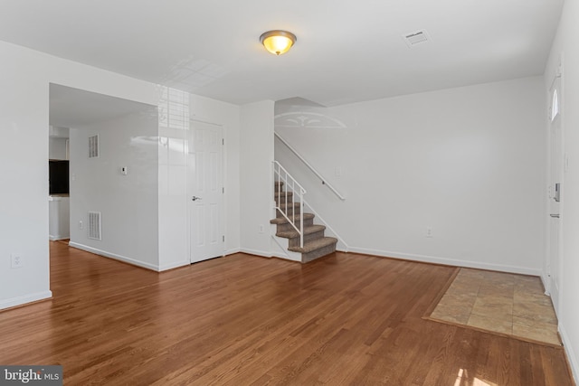 foyer featuring stairs, baseboards, visible vents, and wood finished floors