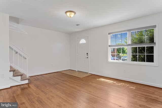 foyer featuring stairway, baseboards, wood finished floors, and visible vents