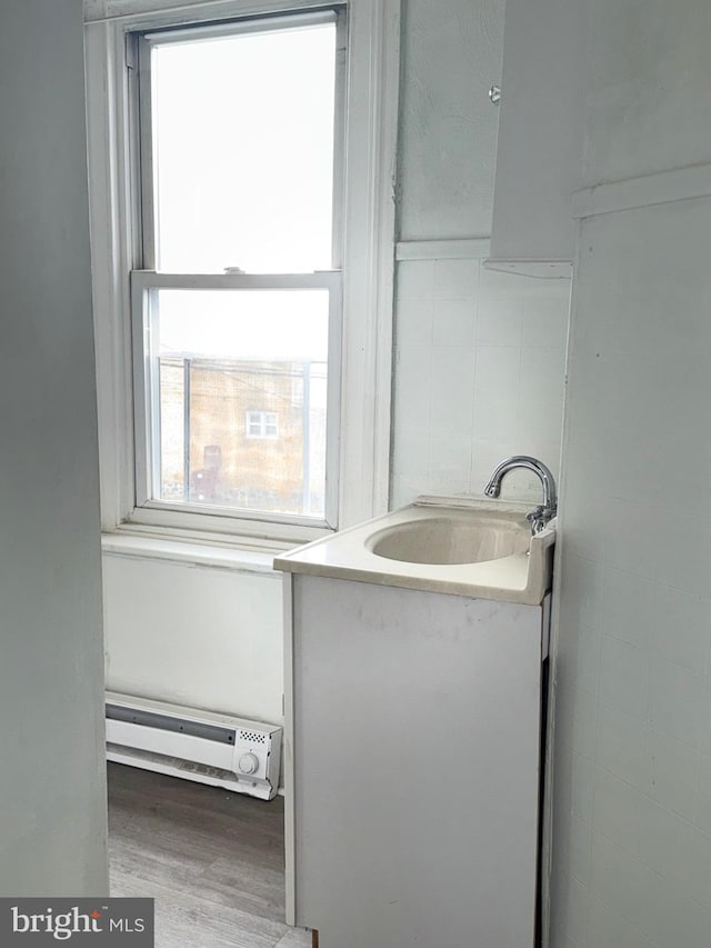 205 E 24th St, Wilmington, DE 19802 - bathroom featuring a baseboard heating unit, vanity, wood finished floors, and tile walls