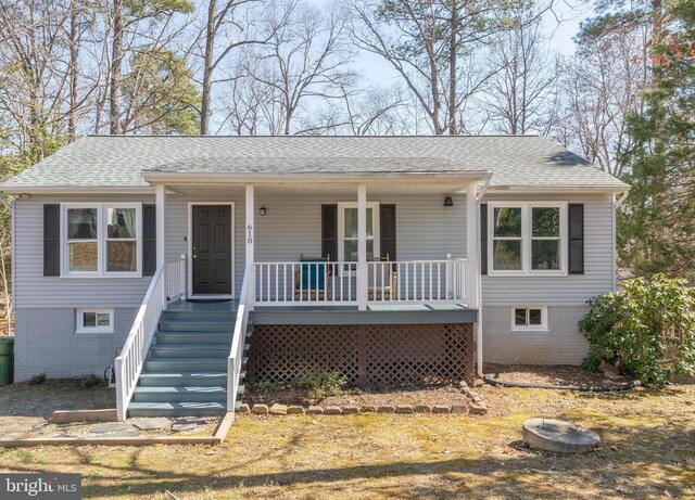 ranch-style home with roof with shingles, a porch, and stairway