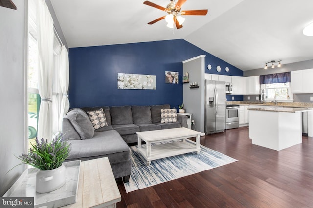 living room with a ceiling fan, vaulted ceiling, and dark wood finished floors