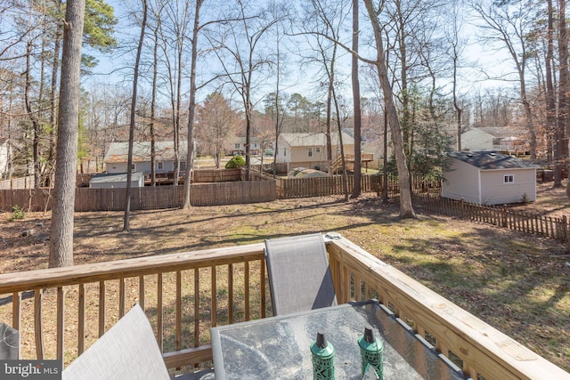 view of yard featuring a fenced backyard, a wooden deck, a residential view, and outdoor dining area