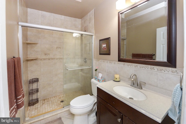 bathroom featuring toilet, tile walls, vanity, and a stall shower