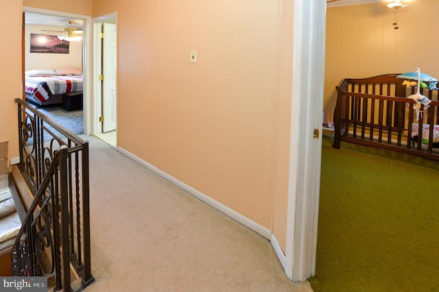 hallway with baseboards, an upstairs landing, and carpet