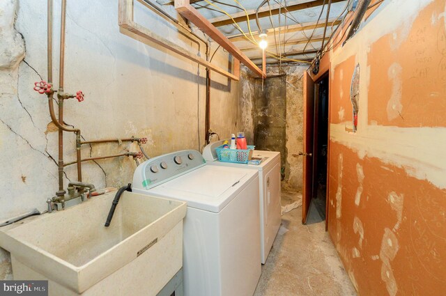 clothes washing area with a sink, independent washer and dryer, and laundry area