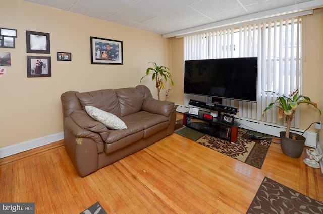 living area featuring baseboard heating, baseboards, and wood finished floors