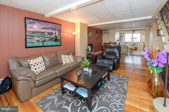 living area with a ceiling fan, wood finished floors, and a paneled ceiling
