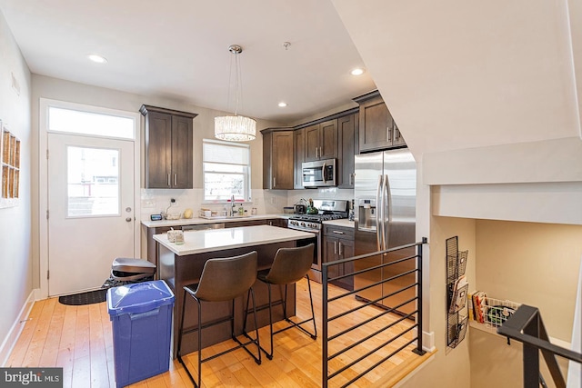kitchen featuring light wood-style floors, dark brown cabinetry, stainless steel appliances, and a center island