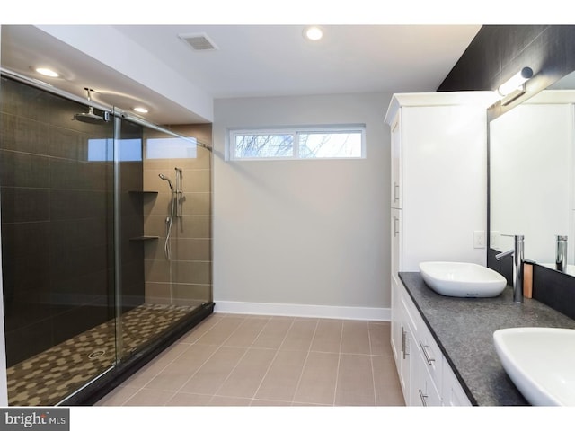full bath with tile patterned floors, a shower stall, a sink, baseboards, and visible vents