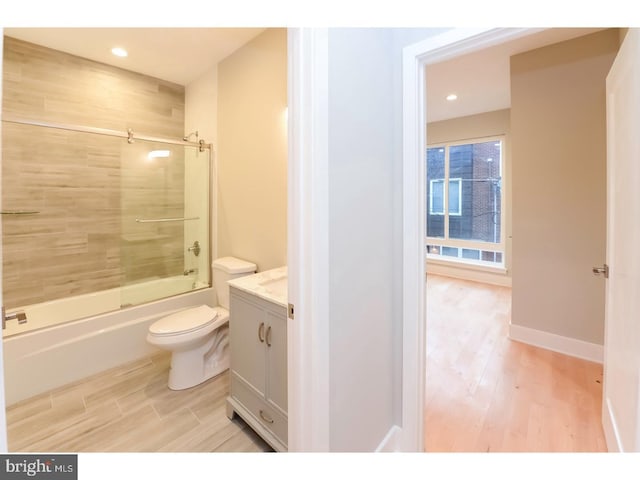 bathroom featuring recessed lighting, wood finished floors, toilet, vanity, and bath / shower combo with glass door