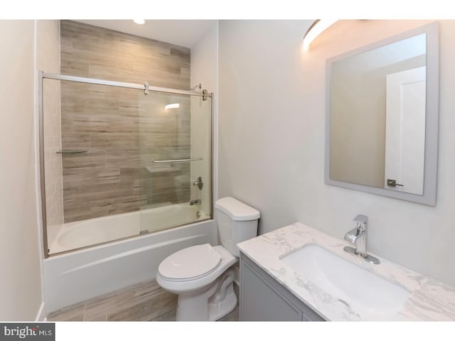 bathroom with toilet, shower / bath combination with glass door, and vanity