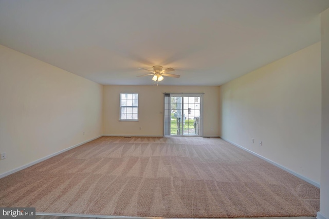 spare room with a ceiling fan, baseboards, and light carpet