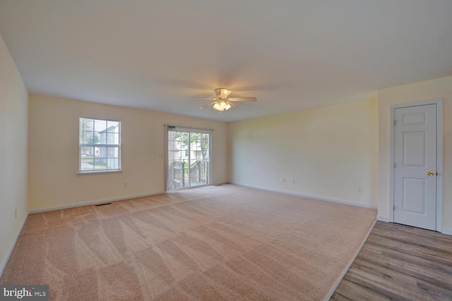 spare room featuring a ceiling fan, visible vents, light colored carpet, and baseboards