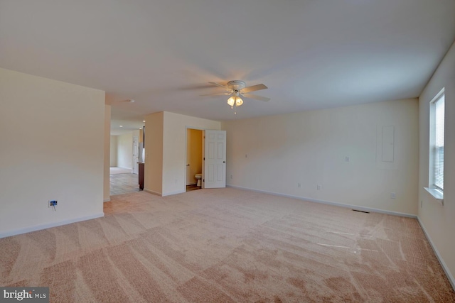 empty room featuring visible vents, ceiling fan, light carpet, and baseboards