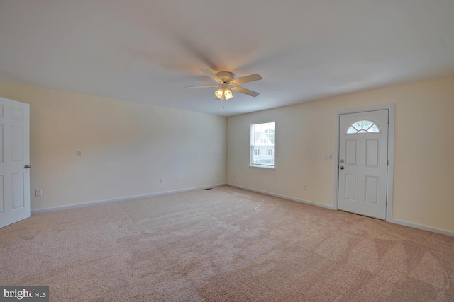 foyer with ceiling fan, light carpet, and baseboards
