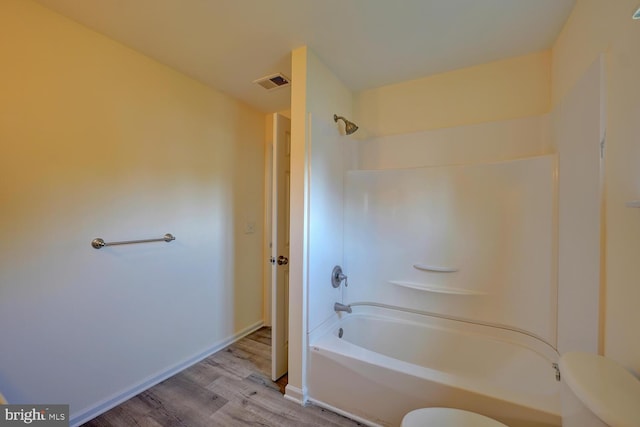 bathroom featuring wood finished floors, visible vents, toilet, and shower / bathtub combination