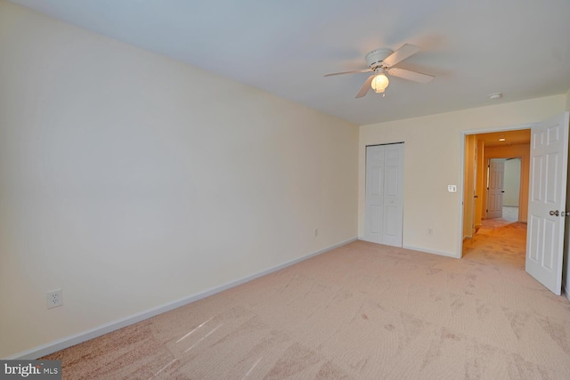 unfurnished bedroom with baseboards, ceiling fan, a closet, and light colored carpet