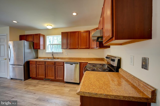kitchen featuring appliances with stainless steel finishes, a sink, light wood-style flooring, and under cabinet range hood