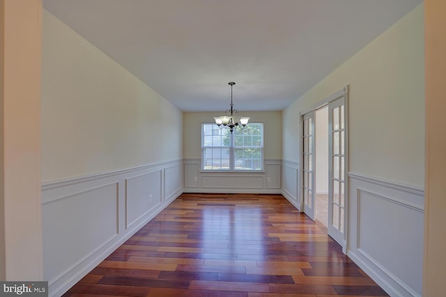 170 Otter Way, Frederica, DE 19946 - unfurnished dining area featuring a chandelier, dark wood-style flooring, a wainscoted wall, a decorative wall, and french doors