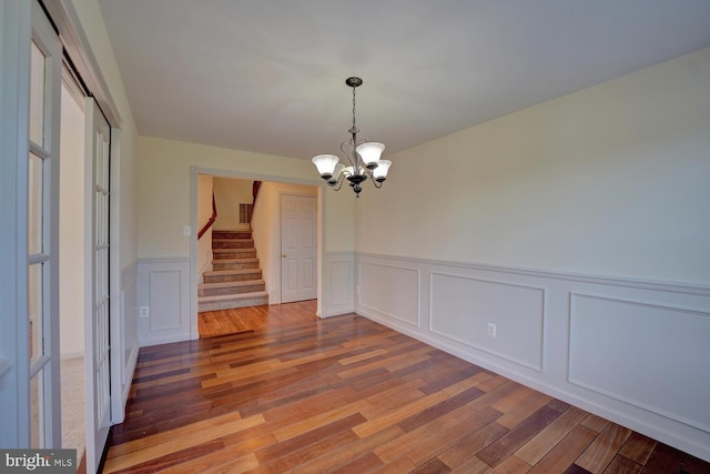 170 Otter Way, Frederica, DE 19946 - unfurnished dining area featuring wood finished floors, a chandelier, wainscoting, stairway, and a decorative wall