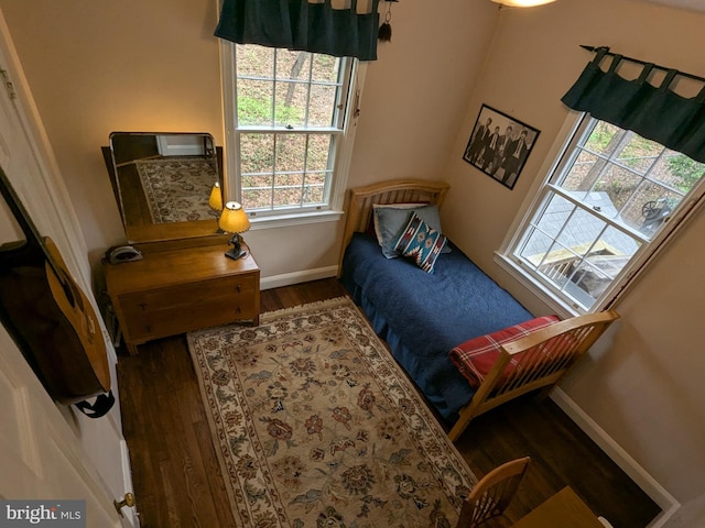 bedroom featuring baseboards, wood finished floors, and multiple windows