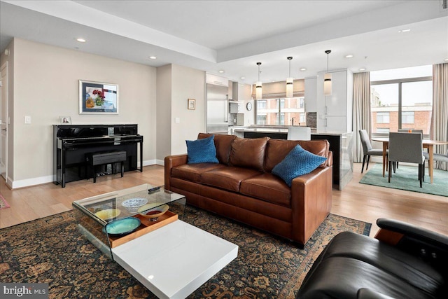 living room featuring baseboards, light wood finished floors, and recessed lighting
