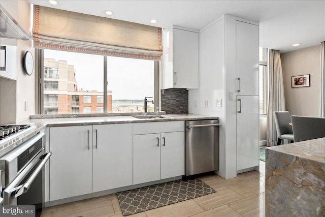 kitchen featuring white cabinets, recessed lighting, backsplash, a sink, and appliances with stainless steel finishes