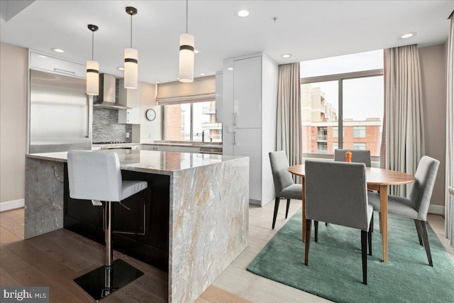 kitchen featuring modern cabinets, decorative backsplash, wall chimney exhaust hood, and white cabinetry