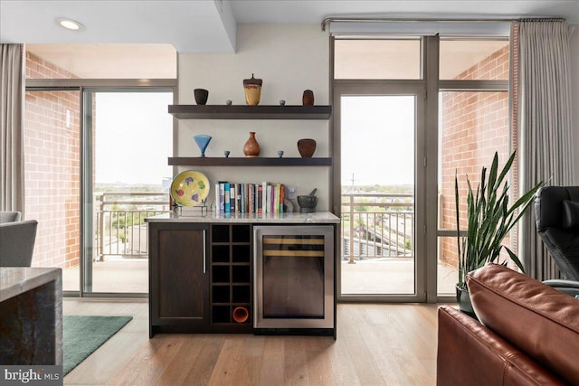 interior space featuring beverage cooler, a bar, light wood finished floors, and recessed lighting