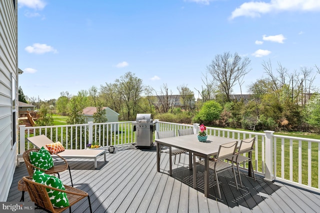 deck featuring outdoor dining area, a lawn, and a grill