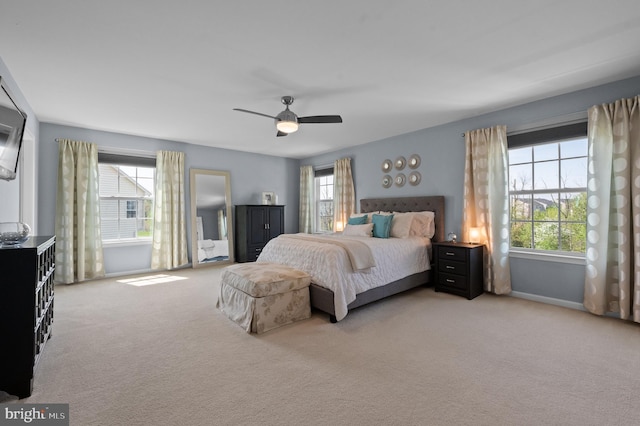 bedroom with baseboards, multiple windows, a ceiling fan, and light colored carpet