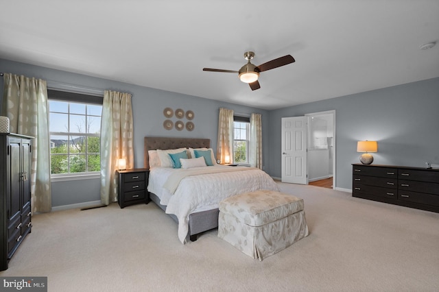 bedroom with baseboards, multiple windows, and light colored carpet