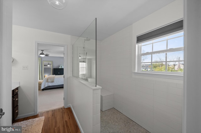 ensuite bathroom with connected bathroom, ceiling fan, walk in shower, vanity, and wood finished floors