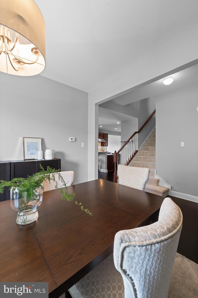 dining space with baseboards, stairs, and a notable chandelier