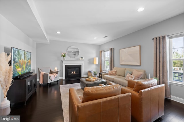 living area with visible vents, baseboards, dark wood-style floors, recessed lighting, and a fireplace with flush hearth