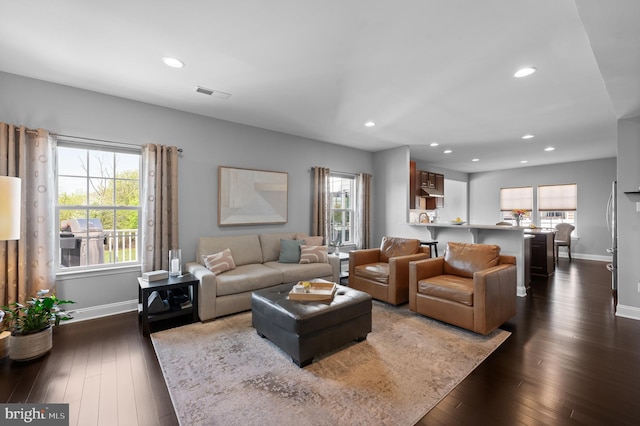 living room featuring visible vents, a healthy amount of sunlight, and dark wood-type flooring