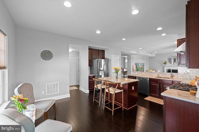 kitchen with a kitchen breakfast bar, visible vents, a sink, stainless steel fridge with ice dispenser, and dishwashing machine