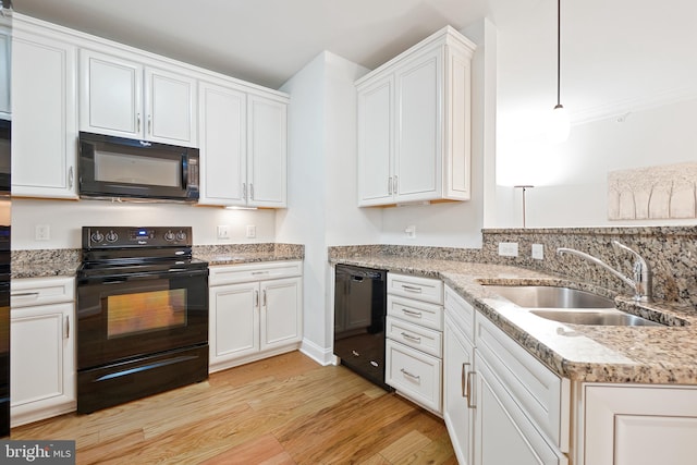 kitchen with white cabinets, light wood finished floors, light stone counters, a sink, and black appliances