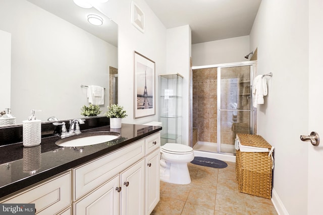 bathroom featuring a shower stall, toilet, vanity, and tile patterned floors