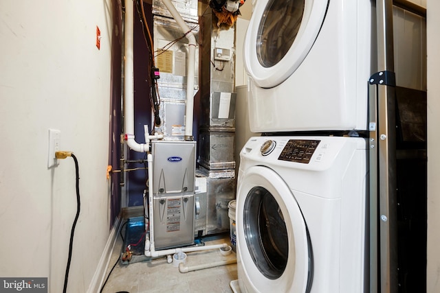 laundry area with baseboards, stacked washer / dryer, and laundry area