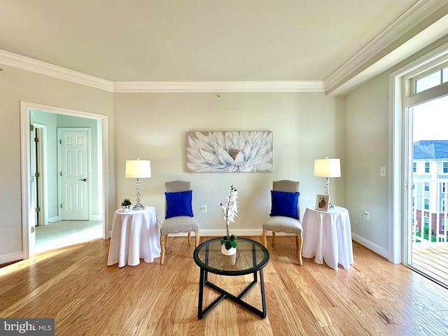 sitting room featuring baseboards, ornamental molding, and light wood finished floors