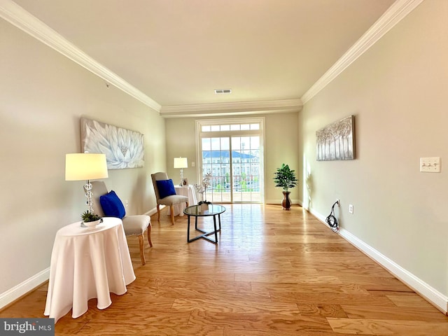 sitting room with visible vents, baseboards, wood finished floors, and crown molding