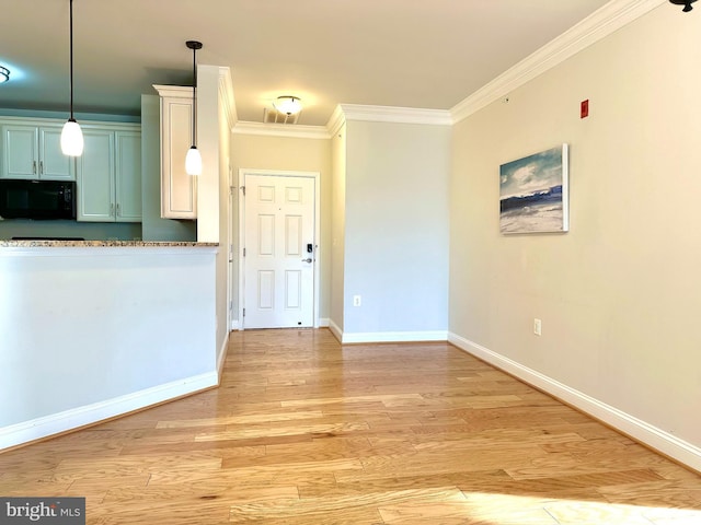 kitchen with light wood-style flooring, baseboards, pendant lighting, black microwave, and ornamental molding