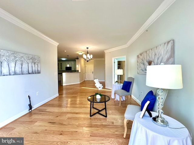living room with light wood-style floors, crown molding, baseboards, and an inviting chandelier