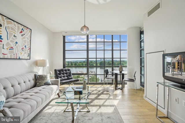 living area with visible vents, expansive windows, plenty of natural light, and wood finished floors