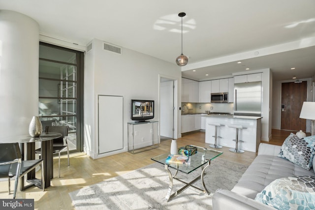 living room featuring light wood finished floors, visible vents, and recessed lighting