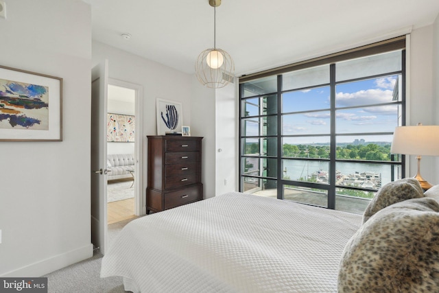 bedroom with a water view, a wall of windows, baseboards, and carpet