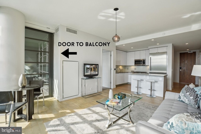 living room featuring recessed lighting, light wood-style flooring, and visible vents