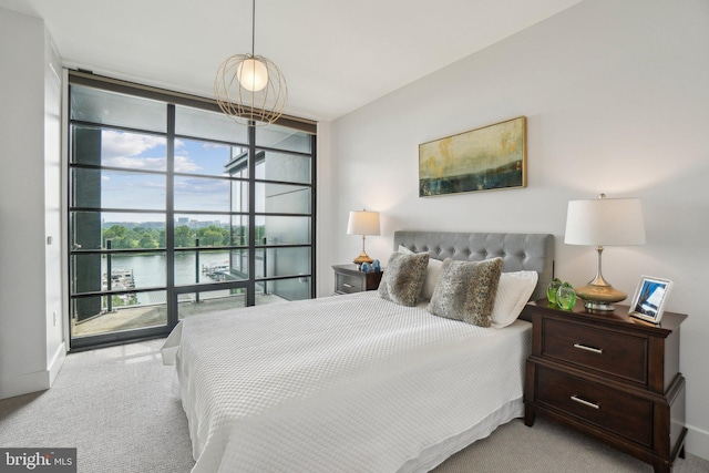 bedroom featuring expansive windows, a water view, and carpet floors