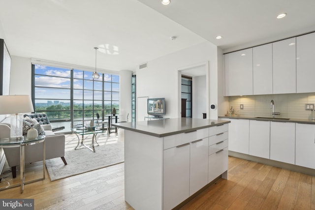 kitchen with dark countertops, expansive windows, modern cabinets, and a sink